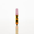 A single small vape cartridge standing upright on a reflective white surface against a seamless white background. The cartridge has a translucent pink mouthpiece, a clear body showing amber-colored liquid, and a black and gold patterned label. Thumbnail