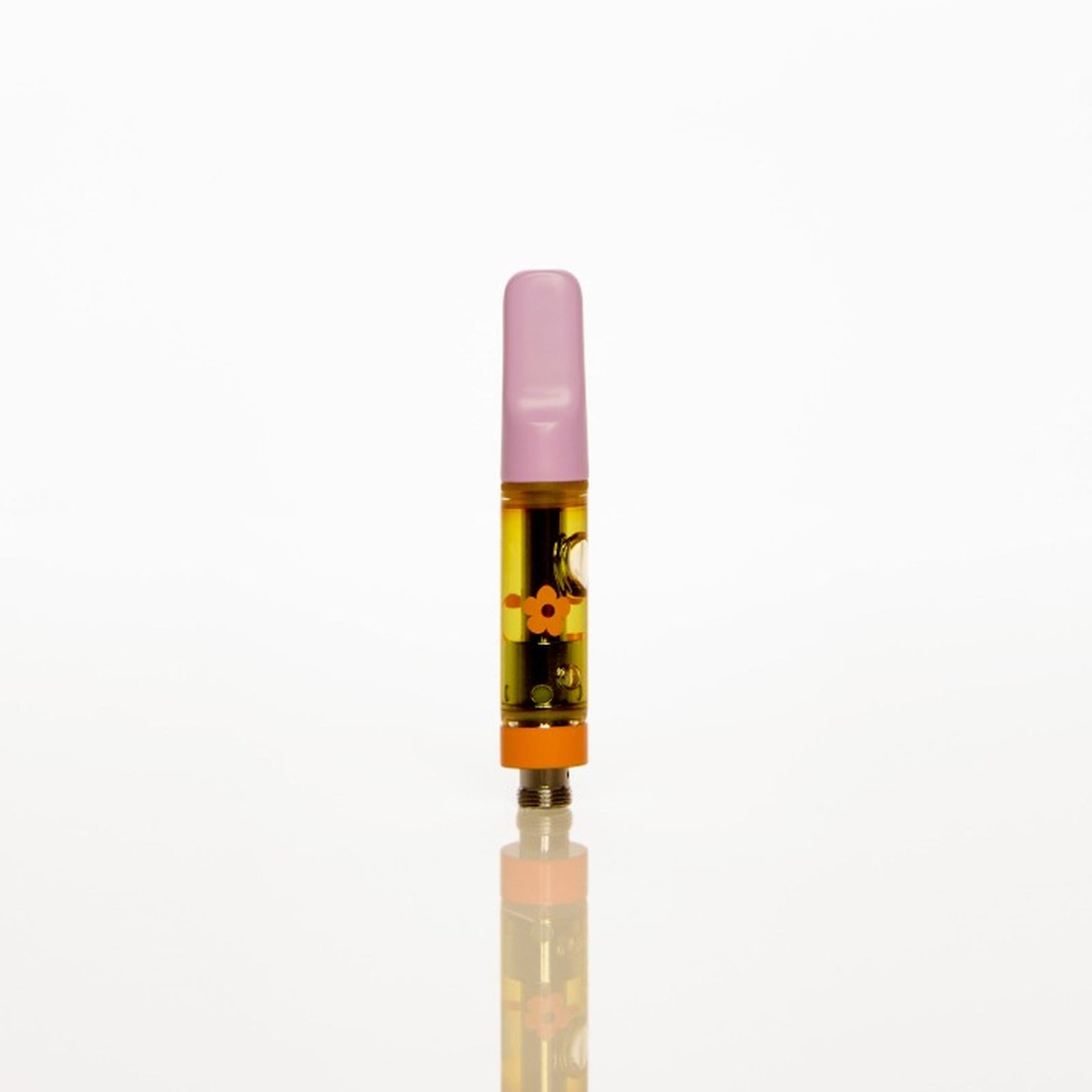 A single small vape cartridge standing upright on a reflective white surface against a seamless white background. The cartridge has a translucent pink mouthpiece, a clear body showing amber-colored liquid, and a black and gold patterned label.
