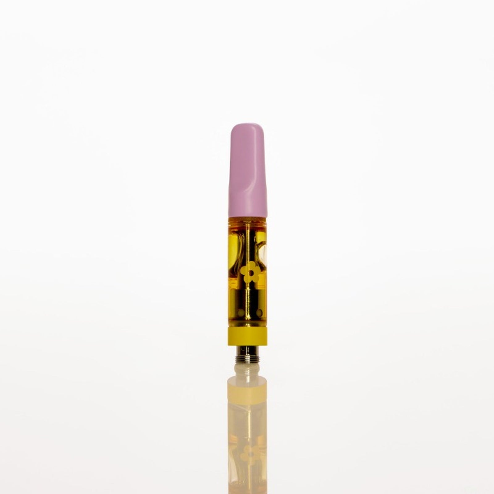 A single disposable vape cartridge standing upright on a reflective white surface against a solid white background. The vape has a light pink mouthpiece, a clear body showing yellow oil, and a black and gold patterned inner section.