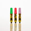 Three small vape cartridges with translucent yellow bodies and colored tops in green, red, and purple, standing upright on a reflective white surface against a white background. Thumbnail