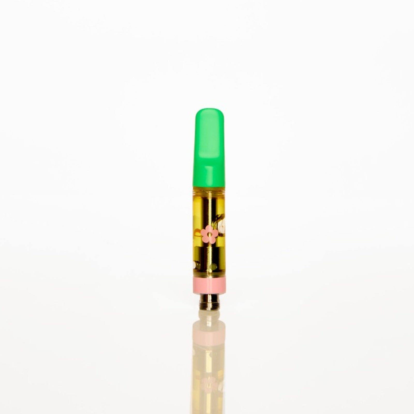 A single disposable vape cartridge standing upright on a reflective white surface against a solid white background. The vape has a bright green mouthpiece, a clear body showing golden-yellow liquid inside, and a metallic pink base.